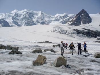 People on snowcapped mountain against clear sky