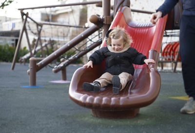 Happy baby girl sliding,warm clothing child,kid,toddler, infant of 1-2 year having fun in playground