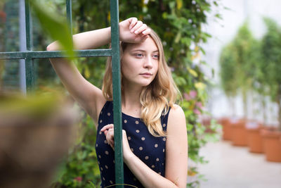 Portrait of beautiful young woman standing against plants