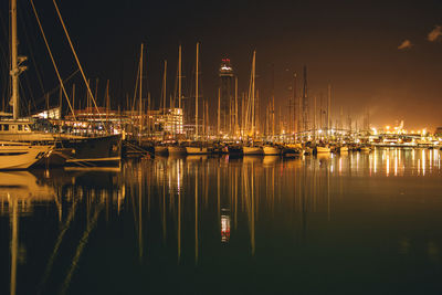 Sailboats moored in harbor at night