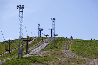 Electricity pylon on field against clear sky