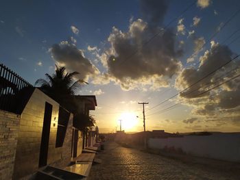 Street amidst buildings against sky during sunset