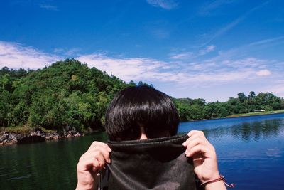Woman with face covered by fabric against lake