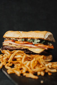 Close-up of burger on cutting board against black background