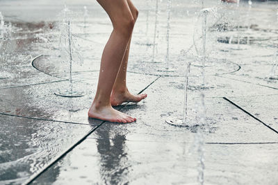 Low section of person jumping at water fountain