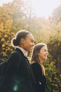 Side view of a smiling young woman against trees