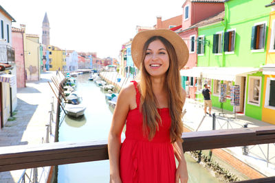Smiling young woman wearing hat standing by canal