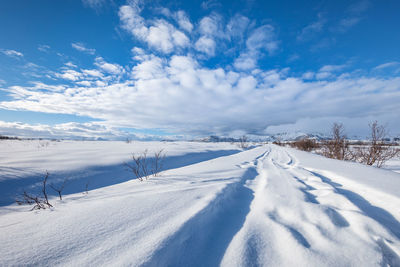 Snow covered landscape against blue sky