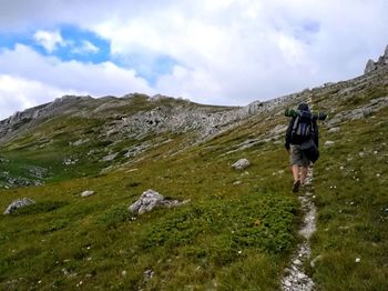 Rear view of woman walking on trail against sky