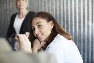 Mature female professional sitting with colleagues in board room during meeting