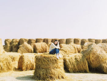 Full length of woman sitting on hay bale