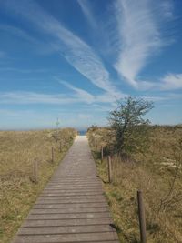 Footpath amidst field against sky