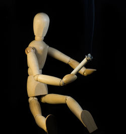 Close-up of figurine with cigarette on black background