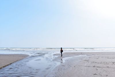 Man on beach against clear sky