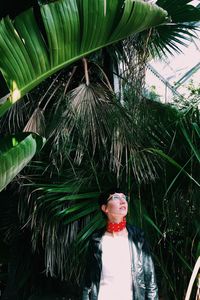 Woman standing by palm tree