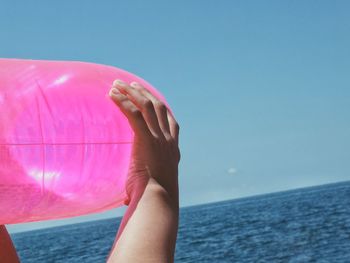 Close-up of hand holding sea against sky