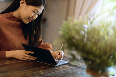 Beautiful woman writing in book at table