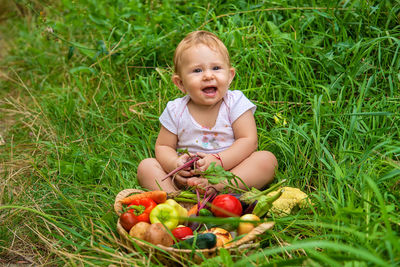 Portrait of cute baby girl sitting on grassy field