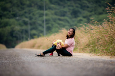 Full length of woman sitting on road