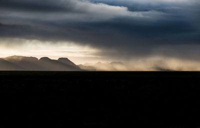 Silhouette of landscape against cloudy sky