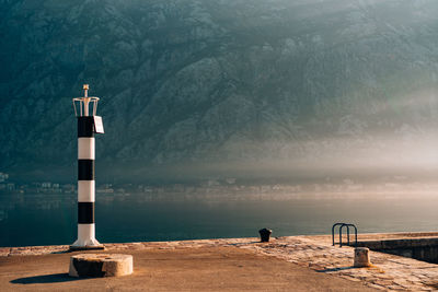 Lighthouse by sea against mountain