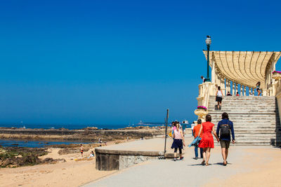 Rear view of people on beach against clear sky