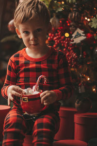 Portrait of cute girl playing with christmas tree at home