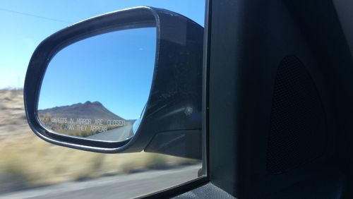 Reflection of car on side-view mirror against clear sky