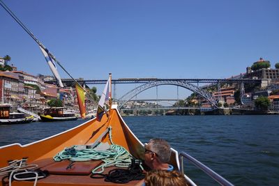 Man on boat sailing in river at city against clear blue sky