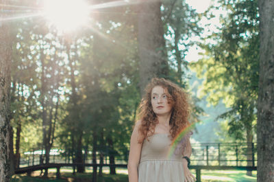 Young woman standing against trees