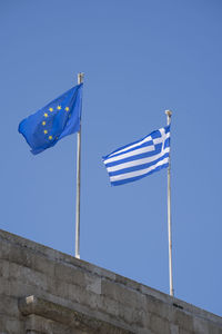 European and the greece flag against blue sky