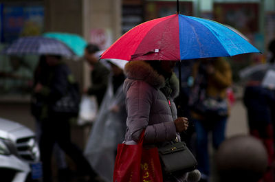 Woman holding umbrella standing on street