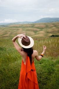 Rear view of woman standing on field against sky