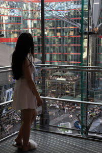 Rear view of woman standing against glass building