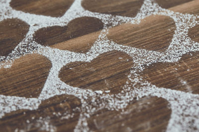 High angle view of heart shapes amidst powdered sugar on table