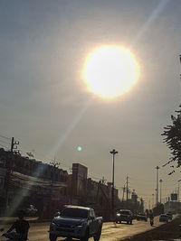 Cars on road against bright sun
