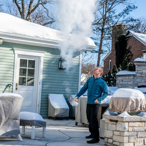 Man throwing snow while standing by house during winter