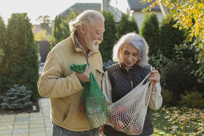 Senior couple carrying groceries in eco-friendly reusable mesh bags