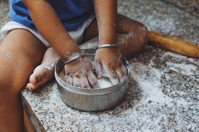 Low section of girl making dough on marble
