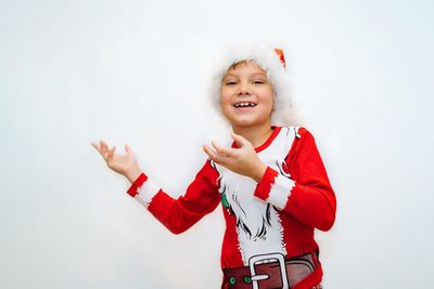 Smiling boy in santa tee shirt and hat pointing to blank space on white background for advertising 