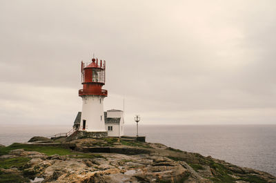 Lighthouse by sea against sky