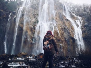 Woman looking at waterfall from cliff