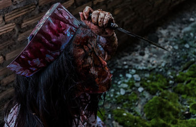 Spooky woman holding knife outdoors