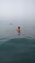 Person swimming in sea against sky