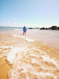 Rear view of man on beach against sky