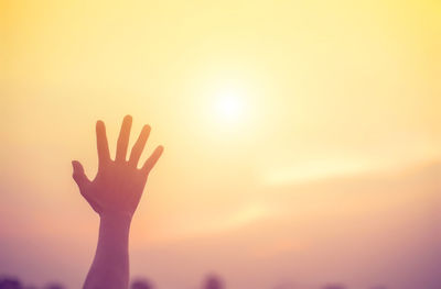 Cropped hand against sky during sunset