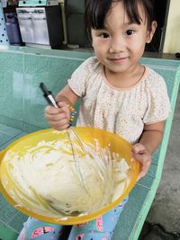 Portrait of girl mixing food in bowl at home