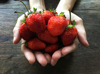 Close-up of human hands holding strawberries on table