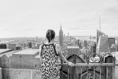 Rear view of woman standing against empire state building in city