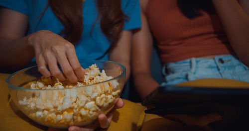 Midsection of friends eating popcorn